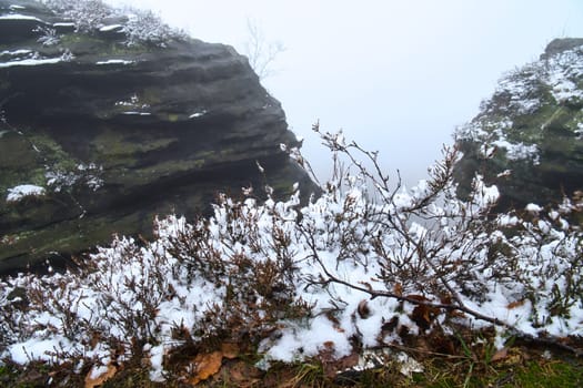 On the large Zschirnstein in fog. Rock covered with snow. Viewpoint during a hike. From the nature park in the Elbe Sandstone Mountains. Landscape in Germany