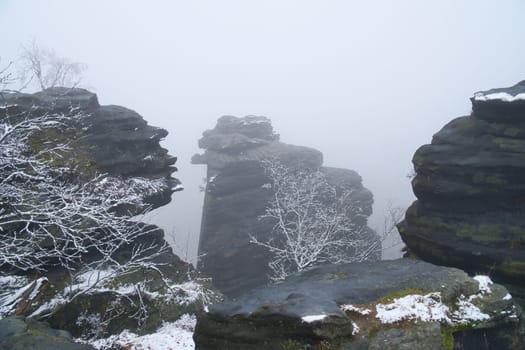 On the large Zschirnstein in fog. Rock covered with snow. Viewpoint during a hike. From the nature park in the Elbe Sandstone Mountains. Landscape in Germany