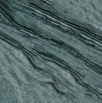 A solid relief surface made of a rough gray base with uneven depressions and lines .Texture or background