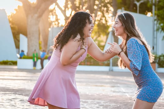 Two happy girls laughing on the street, two women talking and laughing on the street, two women having fun