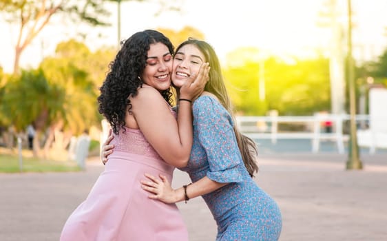 Two female friends hugging in front outdoors, girl friends hugging and enjoying life, women friendship concept