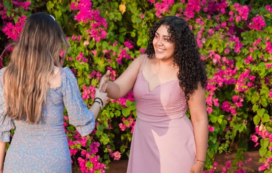 Two girls friends waving and shaking hands, two smiling girls shaking hands on the street