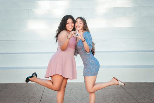 Close up of two girls making a heart shape, two friends together forming a heart, love hands sign
