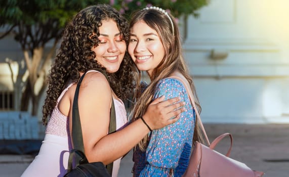 Two female friends hugging in front outdoors, girl friends hugging and enjoying life, women friendship concept