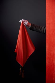 Talent show performance, illusionist entertaining magical trick concept. Closeup hiding magician hand behind red drapery holding magic handkerchief