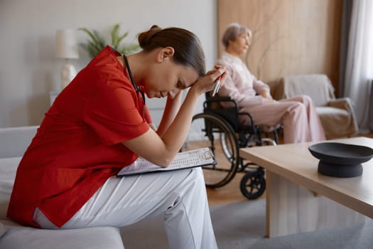 Upset frustrated doctor holding head leaned on patient card feeling disappointed with results of tests analysis and treatment of old senior lady with serious illness disability. Failed rehabilitation