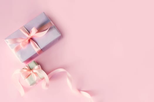 Greeting card with two gift boxes with pink ribbon bows. Top view with space for your greetings on pink background. Spring holiday, present. Valentine, mother, father day.