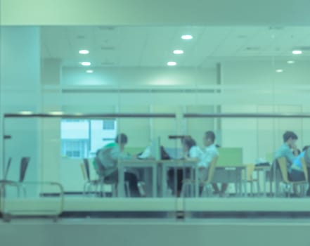 Blurry reading area in public library. Green toned image.