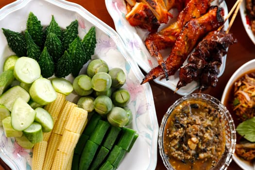 Local Thai food for people in the central region of Thailand. Spicy frog salad with vegetables and herbs. grilled chicken.
