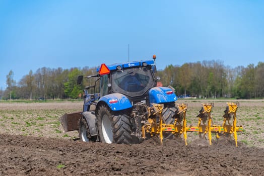 EMMELOORD, NETHERLANDS - APRIL 21, 2018: Farmer with his tractor plowing his land in early spring