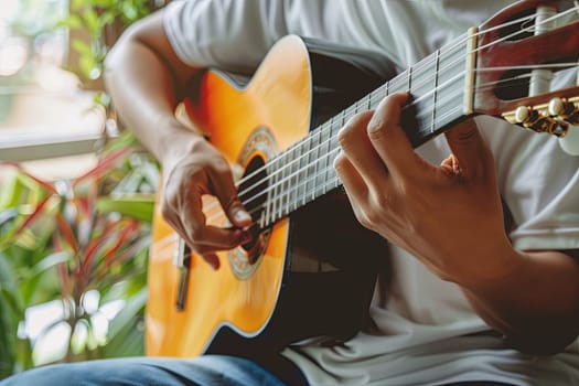 A man is sitting in a room, strumming a guitar with focused concentration. Sunlight filters through the window, casting shadows on the walls as he plays his instrument.