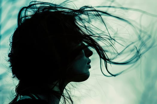 A woman standing outdoors with her hair being blown by the wind. Her hair is flowing and fluttering in the breeze as she looks ahead.