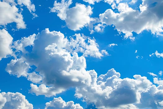 A blue sky filled with lots of white clouds, creating a picturesque scene of nature. The clouds are fluffy and scattered throughout the sky, adding texture and depth to the expansive blue background.