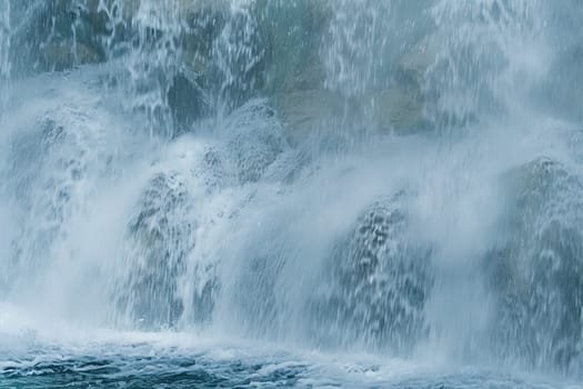 A man is skillfully riding a surfboard in the majestic setting of a powerful waterfall. The surfer is seen gliding on the water, balancing his movements as he gets ready to catch a wave. The waterfall provides a stunning backdrop to this thrilling water sport activity.