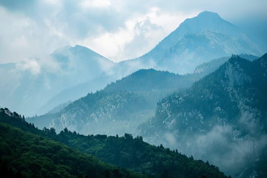 A view of a mountain range covered in thick clouds. The peaks of the mountains are obscured by the mist, creating a mysterious and dramatic scene.