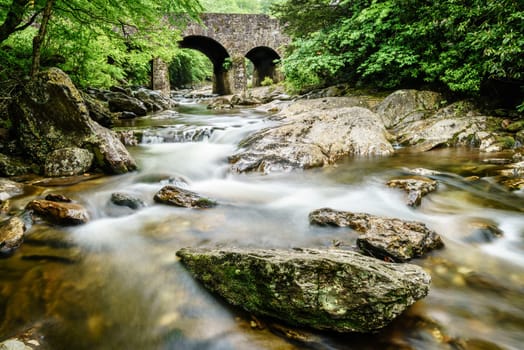 Long exposure image of West Fork Pigeon River under Tripple Arch Bridge near Maggie Valley, North Carolina.