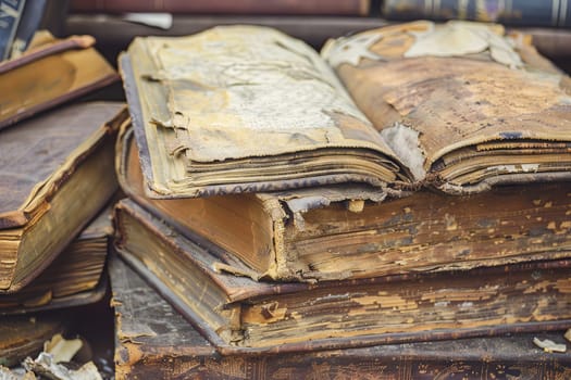 A stack of weathered, aged books is neatly piled on top of a wooden table. The books vary in thickness and color, showcasing a collection of literary works from past eras.