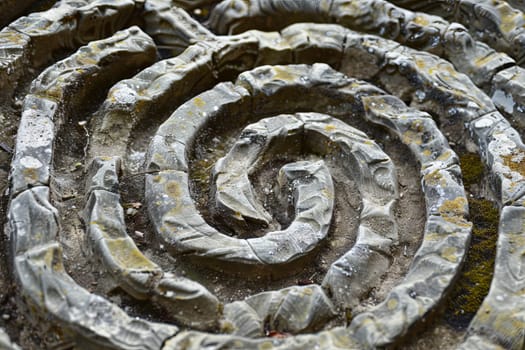 This close-up showcases a detailed spiral design meticulously crafted from small rocks, forming a mesmerizing pattern on the ground. Each rock is carefully placed to create a seamless and harmonious spiral shape that catches the eye.