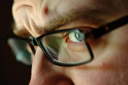 A close-up view of an individual with glasses, showcasing the details of the frames and lenses. The person appears to be looking straight ahead, highlighting the eyewear.