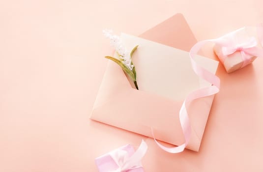 Greeting card with an open envelope and a flower and two gift boxes with pink ribbon with space. Spring vacation, gift, Valentines Day, Mothers Day, Fathers Day. Top view.