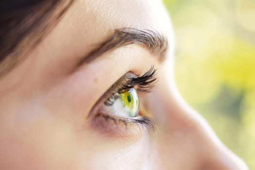 A detailed close-up of a womans eye with a vibrant yellow iris filling the frame. The intricate patterns of the iris and the texture of the eyelashes are clearly visible, creating a striking visual.