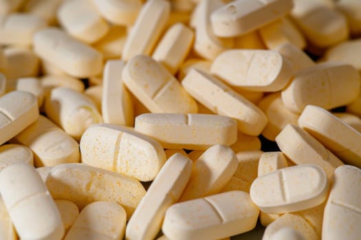 A collection of white pills neatly stacked on top of a wooden table surface. The pills appear to be prescription medication, with each pill bearing a similar round shape. The table is plain and provides a stark contrast to the clinical appearance of the pills.