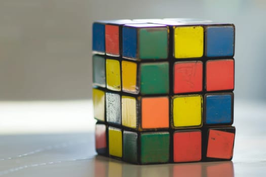 A Rubik cube puzzle is placed on top of a wooden table, showcasing its colorful squares and patterned design.
