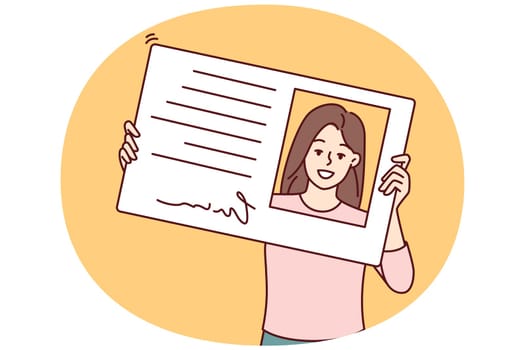 Smiling woman holding driver license or ID card to get access to office or business center. Positive girl looks through plastic ID card designed to authenticate company personnel