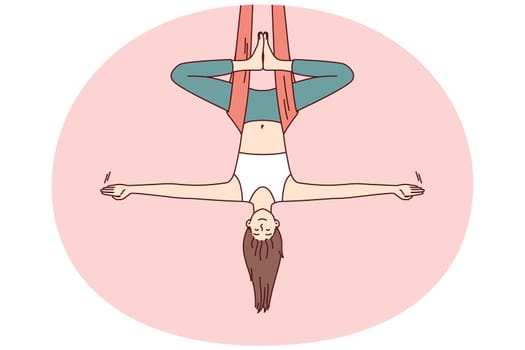 Woman doing aerial yoga hangs upside down in hammock and keeps balance with arms at sides. Girl during workout in yoga studio meditates enjoying practices that cause harmony and get rid of nerves