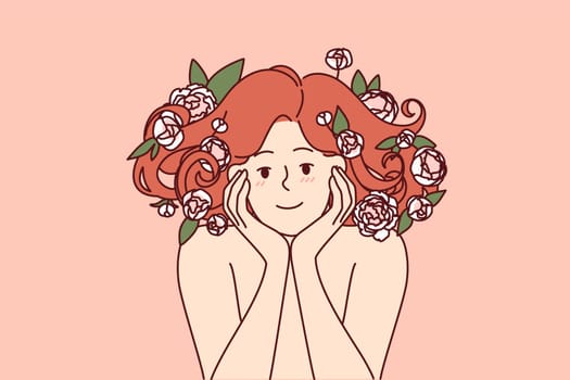 Woman with flowers in beautiful lush hair smiles, recommending use of shampoo based on natural plants. Girl rejoices at opportunity to use cosmetics and shampoo made with addition of rose petals