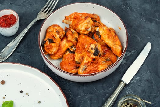 Grilled spicy chicken wings with ketchup on a plate. Baked chicken wings BBQ.