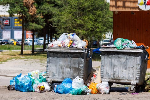 overfilled public trash bins at summer day in Bishkek, Kyrgyzstan - May 26, 2023