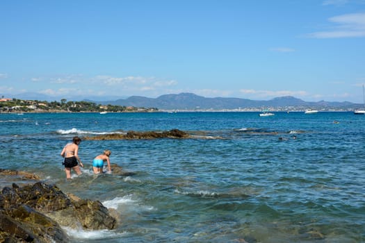 Two children play in the water on a rocky coast on the Côte d’Azur in France