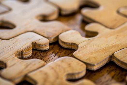 A close up view of a single wooden puzzle piece, showing intricate details and patterns on its surface. The piece is part of a larger puzzle, with visible interlocking edges that suggest connectivity.