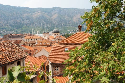 Kotor is a coastal city in Montenegro. Bay of Kotor. Red tiled roofs, mountain and chimneys of a tourist ship. Excursions and tourism. Cathedral of Saint Tryphon. Medieval old towns in the Adriatic.