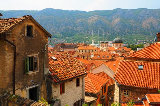 Kotor is a coastal city in Montenegro. Bay of Kotor. Red tiled roofs, mountain and chimneys of a tourist ship. Excursions and tourism. Cathedral of Saint Tryphon. Medieval old towns in the Adriatic.