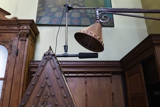 Equipment for prayer and ceremonial chants in Christian Orthodox Church. Microphone on stand, antique bronze earpiece with rivets, wood cabinets, boiserie panels. Kotor Montenegro Church St. Nicholas