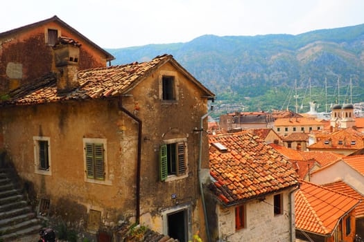 Kotor is a coastal city in Montenegro. Bay of Kotor. Red tiled roofs, mountain and chimneys of a tourist ship. Excursions and tourism. Cathedral of Saint Tryphon. Medieval old towns in the Adriatic.