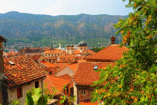 Kotor is a coastal city in Montenegro. Bay of Kotor. Red tiled roofs, mountain and chimneys of a tourist ship. Excursions and tourism. Cathedral of Saint Tryphon. Medieval old towns in the Adriatic.