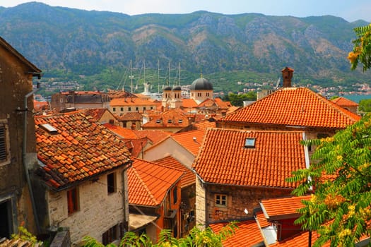 Kotor is a coastal city in Montenegro. Bay of Kotor. Red tiled roofs, mountain and chimneys of a tourist ship. Excursions and tourism. Cathedral of Saint Tryphon. Medieval old towns in the Adriatic.