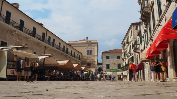 Kotor, Montenegro, 08.11.22: Trg od Oruzja, Arms Square, town square in old city. Square of the Arms. Tourists, women and men, walk along paving stones. Restaurants, souvenir shops. Excursion tourism