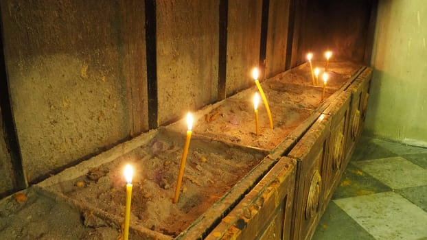 Tall long wax candles burn for repose. Memorial Day with candle. Commemorative candles. Candle flames burn in the cemetery. Burning candles in the Orthodox Church in Kotor, Montenegro. The flame sways