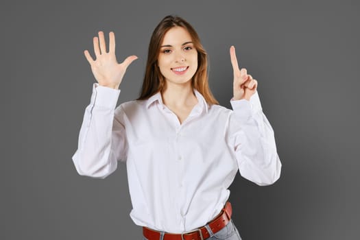 Cheerful woman shows six fingers. Counting with fingers concept.