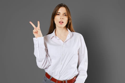 Young woman shows two fingers or victory sign. Counting with fingers concept.