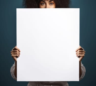 A woman holds a blank white sheet of paper in front of her face.