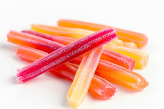 A collection of candy sticks is neatly stacked on top of a pristine white table. The colorful assortment of candies adds a playful touch to the minimalist setting.