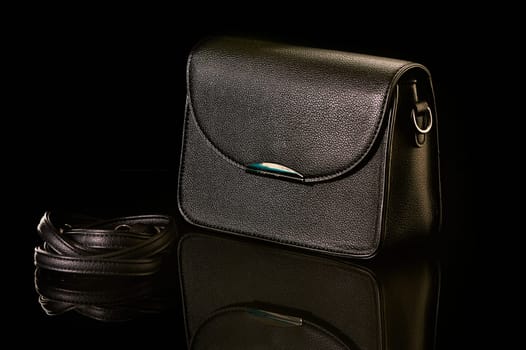 A black handbag stands on black glass. High quality photo