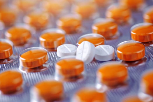A close-up view showing a multitude of orange and white pills clustered together, creating a visually striking pattern. The pills are organized neatly, showcasing their vibrant colors and textures.