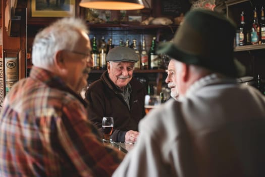 Three men are seated at a bar, engaged in conversation. They appear to be actively discussing topics of interest, leaning in towards one another. The atmosphere is casual and sociable as they exchange ideas and opinions.