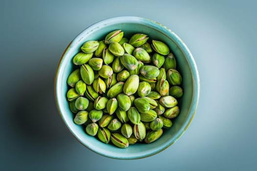 A tranquil scene featuring a vibrant blue bowl overflowing with delicious pistachios, resting gracefully on top of a wooden table.